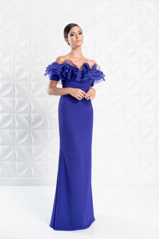 Woman wearing a blue evening gown with ruffled top against a white background